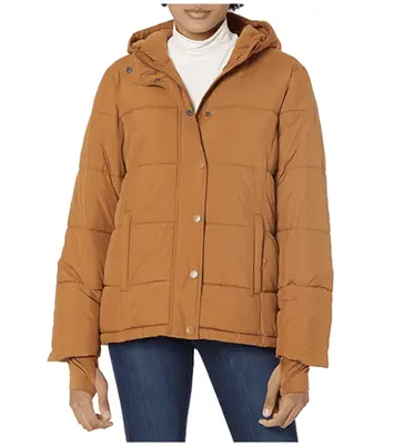 Woman in a yellow fully coat leaning against a wall