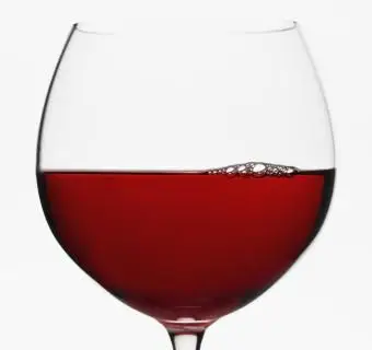 Copa de globo de vino tinto sobre fondo blanco.