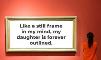 אישה מסתכלת על מסגרת ריקה על קיר אדום